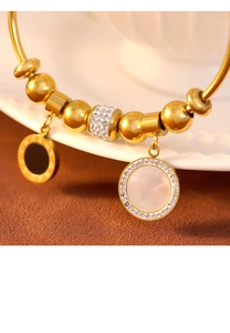 Détail macro du bracelet à billes dorées avec pendentif chiffres romains et nacre blanche