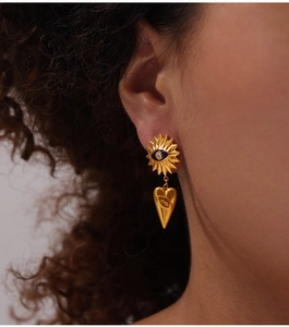 Macro-opname van 18k vergulde evil eye oorbellen met hangende hartvormige bedels