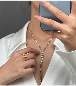 Detailed view of luxury gold-plated ring with diamond-studded sphere and Y-shaped necklace