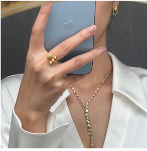 Detailed view of luxury gold jewelry set including open ring and crystal necklace