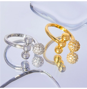 Detailed view of silver and gold rings with spherical pave zircon settings on light purple base