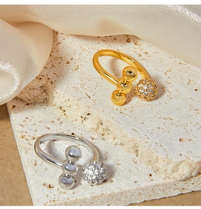 Close-up of gold and silver open rings with micro-pave zircon spheres on silk background