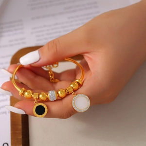 Bracelet à billes dorées avec pendentif chiffres romains et cristaux sur le poignet