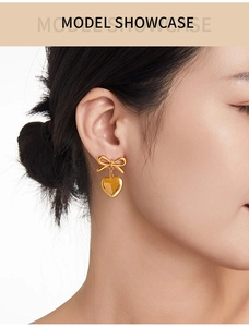 Gros plan de boucles d'oreilles nœud et cœur doré portées par un mannequin chic