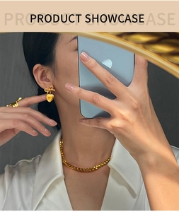 Vue lifestyle chic des boucles d'oreilles nœud cœur doré avec collier corde et bague