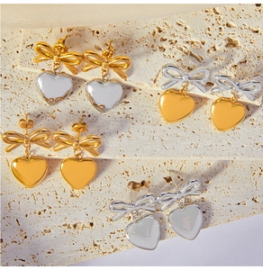 Gros plan de boucles d'oreilles cœur et nœud en or 18 carats et argent poli brillant