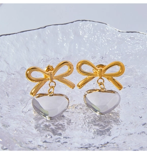 Vue détaillée des boucles d'oreilles nœud plaquées or 18 carats avec cœurs en cristal clair