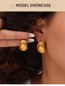 Détails macro des boucles d'oreilles vintage plaquées or 18 carats sur modèle