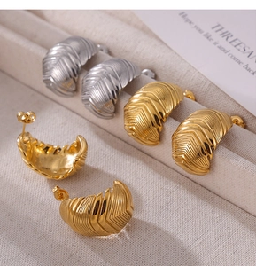 Détail de boucles d'oreilles vintage dorées et argentées à rayures sur plateau velours