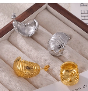 Détail de boucles d'oreilles vintage dorées et argentées à texture plumes sur velours