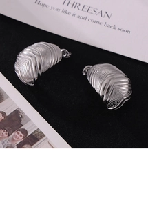 Détail macro de boucles d'oreilles plume argentées avec texture rainurée en V