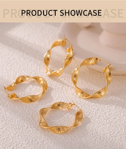 Detail of gold twisted hoop earrings with textured finish on a white stone surface