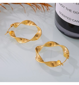 Detailed view of gold twisted hoop earrings with intricate textured pattern and glossy finish