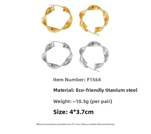 Macro detail of twisted U-shape titanium steel hoop earrings in gold and silver finish