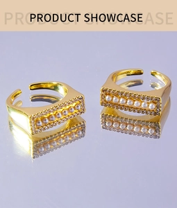 Close-up of two gold-plated open rings with tiny pearls and sparkling zircon accents