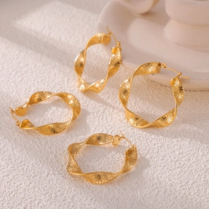 Golden twisted U-shaped earrings with textured dots on a minimalist stone base