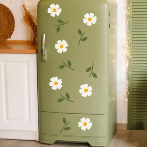 Close-up of white daisy floral wall decals applied on a retro green refrigerator surface