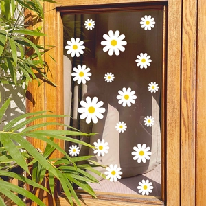 Daisy window decals on glass pane with natural greenery and warm sunlight