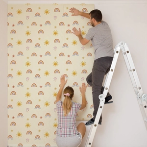 Applying colorful rainbow and sun wallpaper on a bedroom wall with a ladder