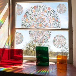Rainbow effect window film with floral mandala patterns reflecting bright sunlight on a desk