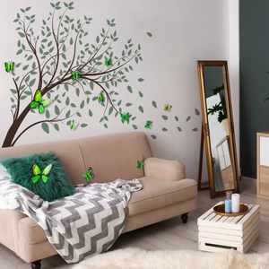 Nature wall sticker set with tree branches and green butterflies above a modern sofa