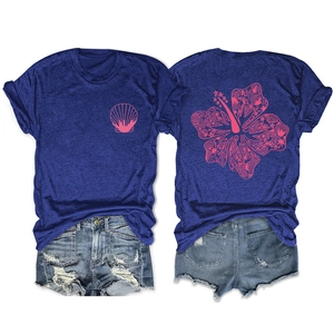 Detail of pink hibiscus flower print with coral and shells on blue cotton t-shirt