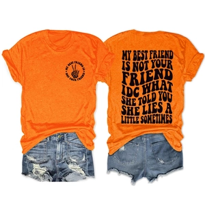 Détail de t-shirt orange avec slogan et short en jean bleu déchiré pour tenue de femme