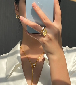 Détail de bague papillon dorée avec cristaux et collier élégant avec perle