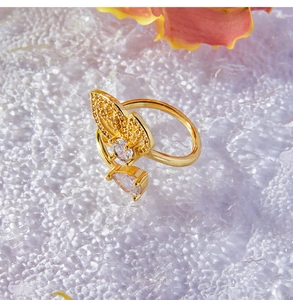 Détail d'une bague papillon dorée avec des zircons sur un fond texturé élégant