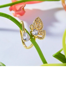 Détail macro d'une bague papillon dorée avec zircons sur une tige naturelle