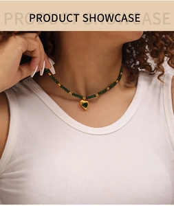 Détail d'un collier bohème avec pendentif cœur vert et perles sur le cou d'un mannequin