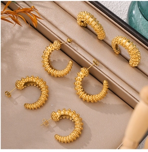 Macro view of C-shaped 18k gold plated titanium earrings with unique beaded texture detail