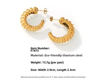 Detailed macro view of 18k gold-plated titanium steel C-shaped earrings with grainy texture