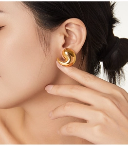 Gros plan d'une boucle d'oreille virgule plaquée or 18 carats montrant un éclat métallique