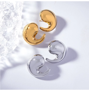 Vue macro de boucles d'oreilles virgules minimalistes en finitions or et argent polis