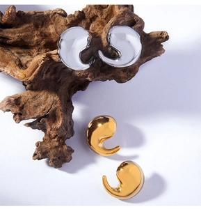 Gros plan de boucles d'oreilles virgule dorées et argentées sur support en bois