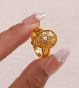 Macro view of gold ring with teardrop pearl and sunburst star texture detailing
