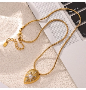 Macro view of gold shell texture pendant with pearl and star engraving on stainless steel chain