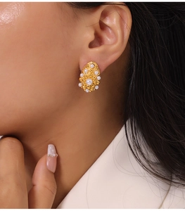 Close-up of a gold-plated geometric earring with pearl inlay worn by a model