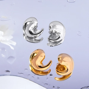 Boucles d'oreilles virgule en or 18 carats et argent sur surface miroir réfléchissante