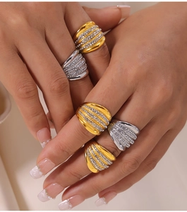 Detail of wide ribbed metal rings with multi-row zirconia stones in gold and silver