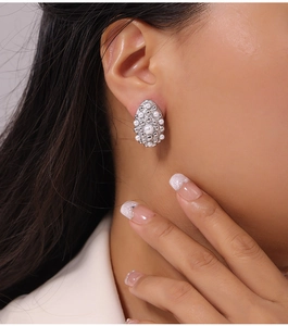 Close-up of shell pearl geometric earrings with gold plating on a female model