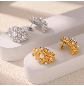 Macro view of geometric gold and silver stud earrings with beaded texture and pearls