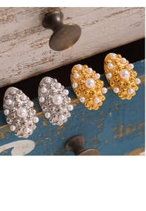Detailed view of geometric gold and silver earrings with white pearls on vintage wood
