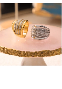 Close-up of wide band gold and silver rings with multi-row pave crystal settings