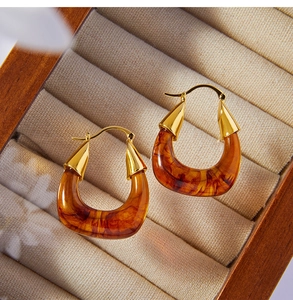 Macro view of retro amber resin U-shaped gold earrings placed in a wooden jewelry box