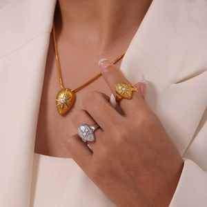 Titanium steel jewelry set with gold starburst pendant and pearl rings on model