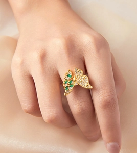 Detalle del anillo de mariposa en oro de 18k con piedras verdes y blancas en seda