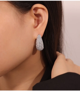 Gros plan de boucles d'oreilles goutte argentées serties de zircons portées par un mannequin