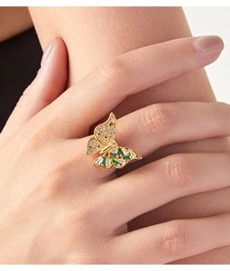 Detalle de anillo mariposa de oro de 18k con circonitas verdes en la mano